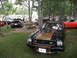 1978 Ford Mustang II - A black 1978 Ford Mustang II with gold racing stripes is displayed at a car show event.