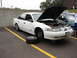 1992 Ford Taurus - White 1992 Ford Taurus undergoing maintenance in a parking lot.