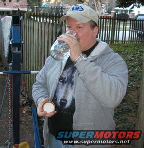 Man drinking from a jar, wearing a wolf t-shirt and a baseball cap