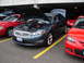 1992 Ford Taurus - A dark blue sedan with both hoods open is parked between two red cars.