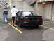 1992 Ford Taurus - A man wipes down the rear of a black 1992 Ford Taurus sedan while another man watches.
