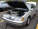1992 Ford Taurus - A silver 1992 Ford Taurus SHO is displayed with its hood open, revealing the engine. A trailer with racing numbers is visible behind it.