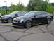 1992 Ford Taurus - Two sedans, a black Cadillac CTS and a gray Pontiac G8, are parked side-by-side in an asphalt lot.