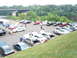 1992 Ford Taurus - A gathering of sedans in a parking lot by a river, with a bridge in the distance.