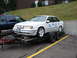 1992 Ford Taurus - A white 1992 Ford Taurus is loaded onto a trailer, with blue racing numbers on its body.