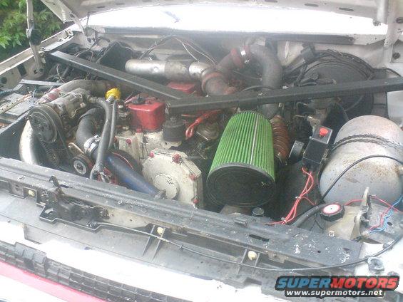 Engine bay with large green air filter, turbocharger, and custom plumbing