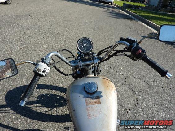 Motorcycle handlebars, gauge, and fuel tank, viewed from rider's perspective