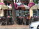 1992 Ford Taurus - A tree partially obscures the view of a restaurant patio with tables and chairs.