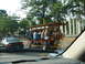 1992 Ford Taurus - A group of people ride a pedal-powered vehicle down a street, passing a car.