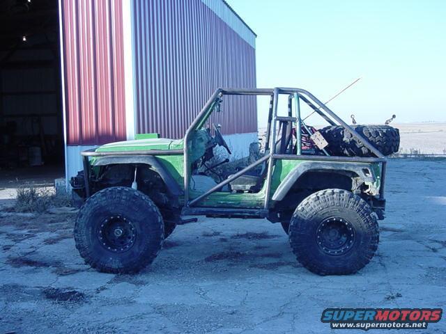 Green off-road vehicle with roll cage and spare tire mounted on back
