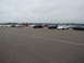 1992 Ford Taurus - A variety of vehicles are parked in a lot, possibly at a car show or event, under an overcast sky.