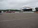 1992 Ford Taurus - Several cars are parked on a paved area, possibly a racetrack, with a covered structure in the background.