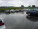 1992 Ford Taurus - Several cars are parked on a wet track surface under an overcast sky.