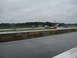 1992 Ford Taurus - A red car and a white van are on a wet race track with trees and a fence in the background.