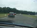 1992 Ford Taurus - A dark 1992 Ford Taurus drives on a wet track with other vehicles in the distance.