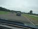 1992 Ford Taurus - A dark sedan drives on a race track with other cars visible in the distance under a cloudy sky.