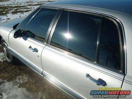 Silver sedan side view, sun glare on windows, chrome trim, some snow on ground