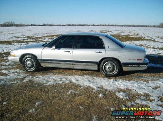 Silver sedan parked on a dirt and snow covered field. The car is viewed from the side