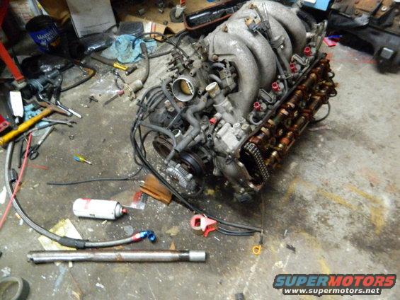Engine on a garage floor with tools and parts scattered around