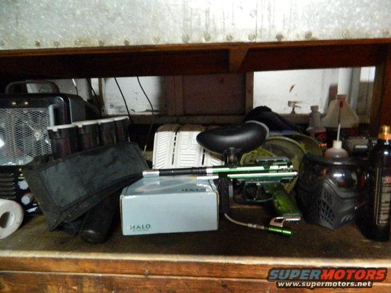Paintball gun, mask, and loader box on a shelf