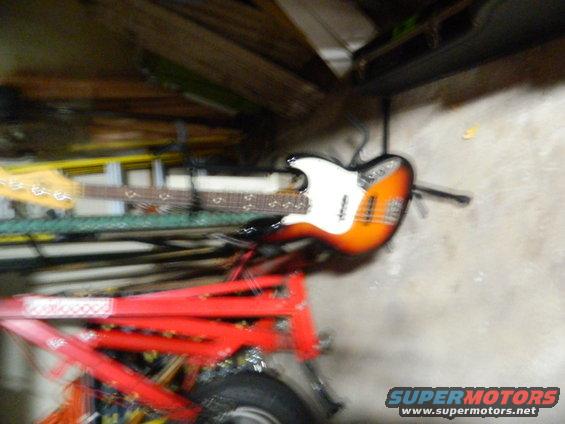 Orange and white electric guitar hanging on a stand