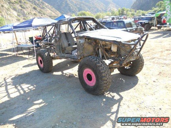 Off-road buggy with roll cage and pink wheel accents, front view