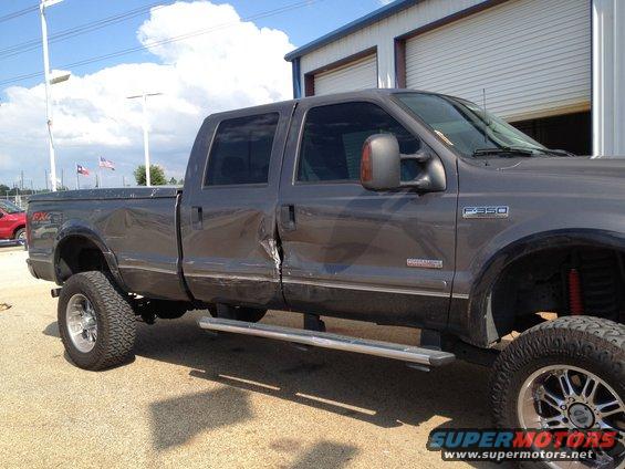 Gray 2006 Ford F-350 Super Duty with significant damage to the driver's side doors and body panels