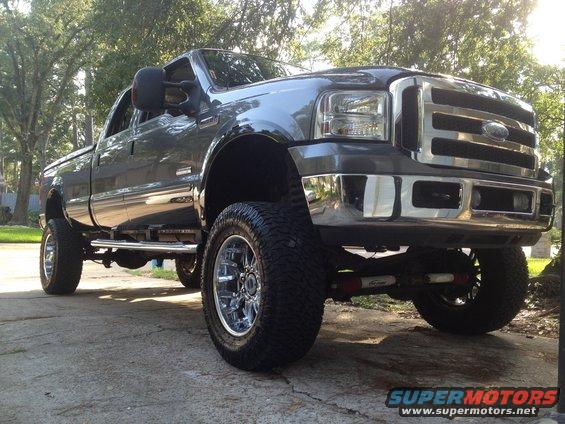 Lifted dark gray Ford Super Duty pickup truck, front quarter view. Chrome grille and wheels
