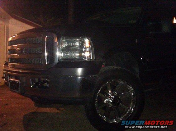 Black Ford Super Duty truck front corner with chrome grille and headlights. Year is 2005