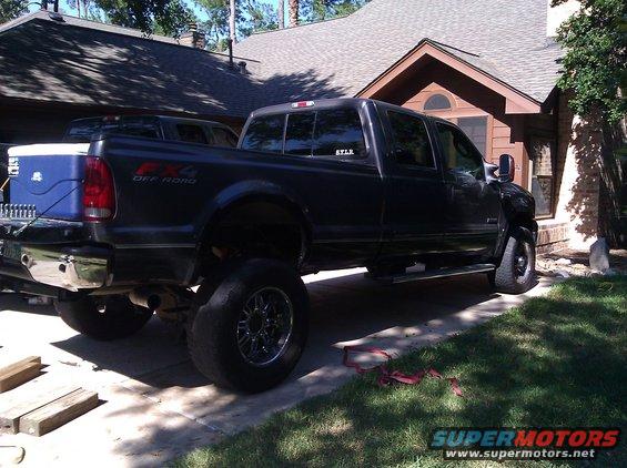Dark gray Ford F-350 pickup truck parked in driveway, another truck behind it