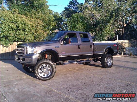 Gray lifted pickup truck with chrome wheels and black trim, seen from a 3/4 front angle