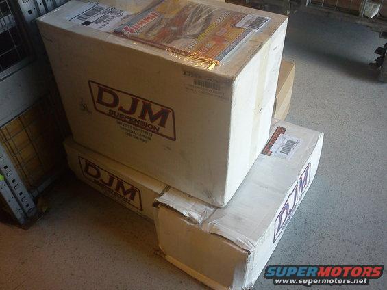 Boxes of DJM Suspension parts stacked up. A Summit Racing catalog is on top