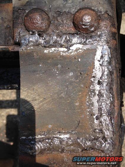Close-up of a rusty metal frame with visible welds and two large bolts