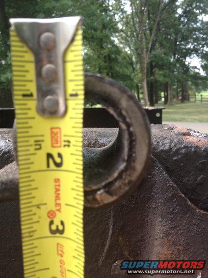 Tape measure next to a metal loop on a rusty object