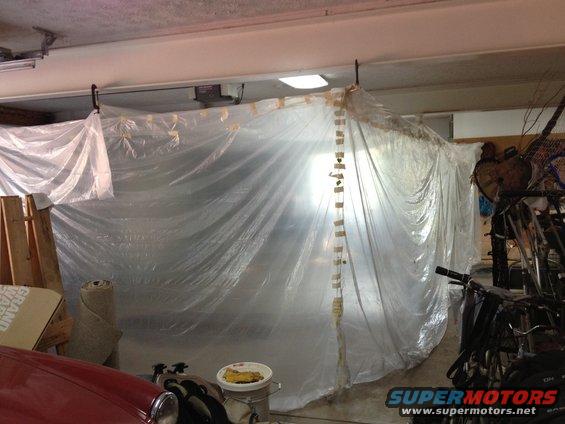 Vehicle covered in plastic sheeting in a garage