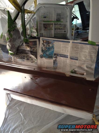 vehicle interior covered in newspaper for painting, showing door panel and dashboard area