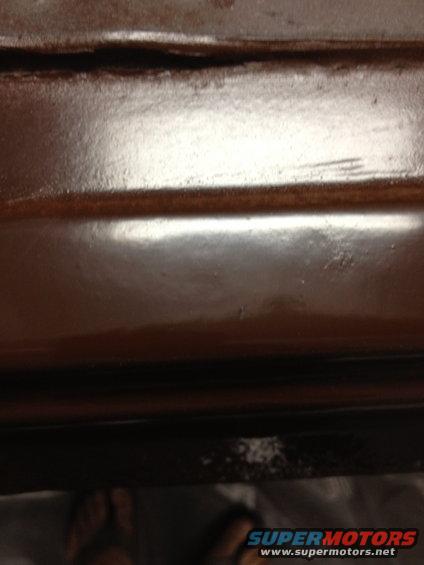 Close-up of a dark brown, possibly wood-grain, interior car panel with a shiny finish and a visible seam