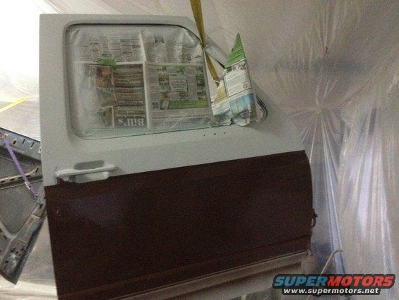 Car door covered in newspaper for painting, with a dark brown lower section