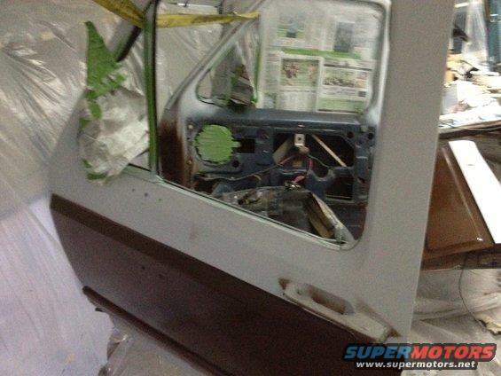 Car door open showing interior components and wiring. Newspaper is taped to the window