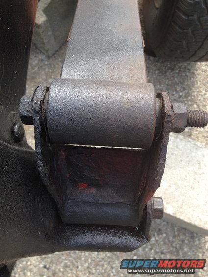 Close-up of a vehicle's leaf spring mount with a bolt and nut