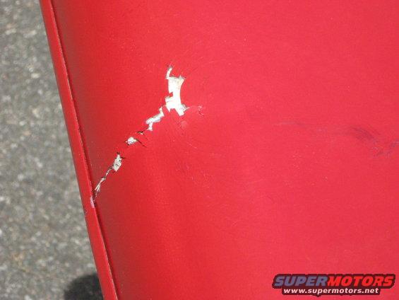 Red surface with chipped paint and scuff marks. A watermark reads SUPERMOTORS