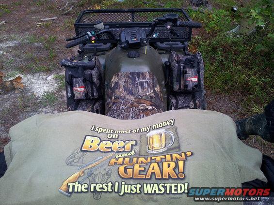 Camouflaged all-terrain vehicle with saddlebags and a rack, viewed from above with a t-shirt in the foreground