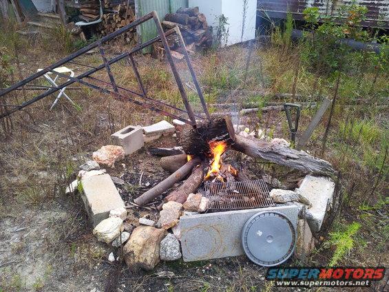 Campfire with logs and a grill, surrounded by cinder blocks and rocks