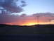 1992 Ford Taurus - A vibrant sunset paints the sky with hues of orange, pink, and purple over a distant mountain range.