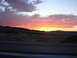 1992 Ford Taurus - A vibrant sunset paints the sky over a rural landscape, with a highway visible in the foreground.