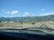 1992 Ford Taurus - View from inside a vehicle driving on a highway with mountains in the distance under a blue sky with clouds.