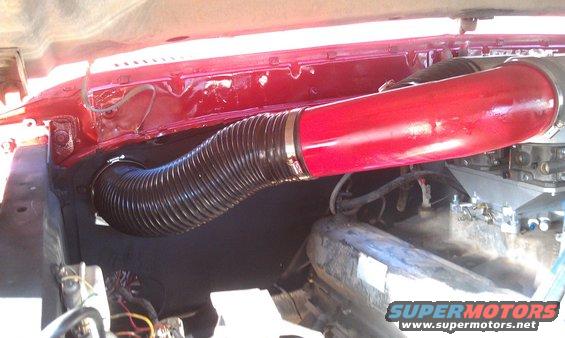 Engine bay showing a red intake tube connected to a black flexible hose