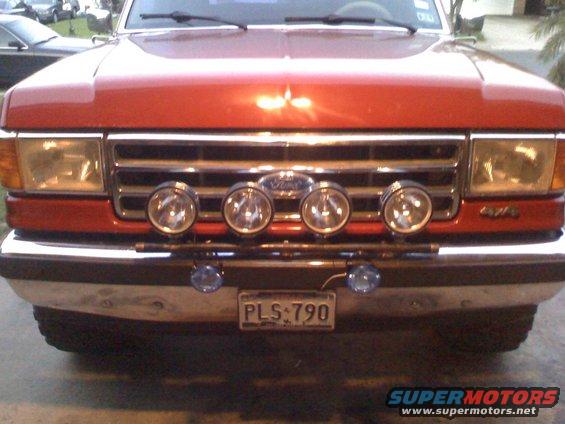 Red Ford truck front grille with four driving lights and "4x4" badge