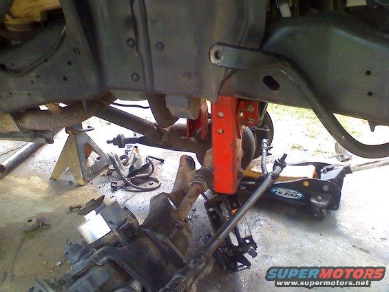 Red suspension lift components on vehicle undercarriage