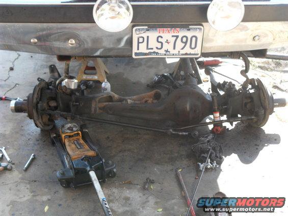 Vehicle rear axle assembly on jack stands with a floor jack underneath